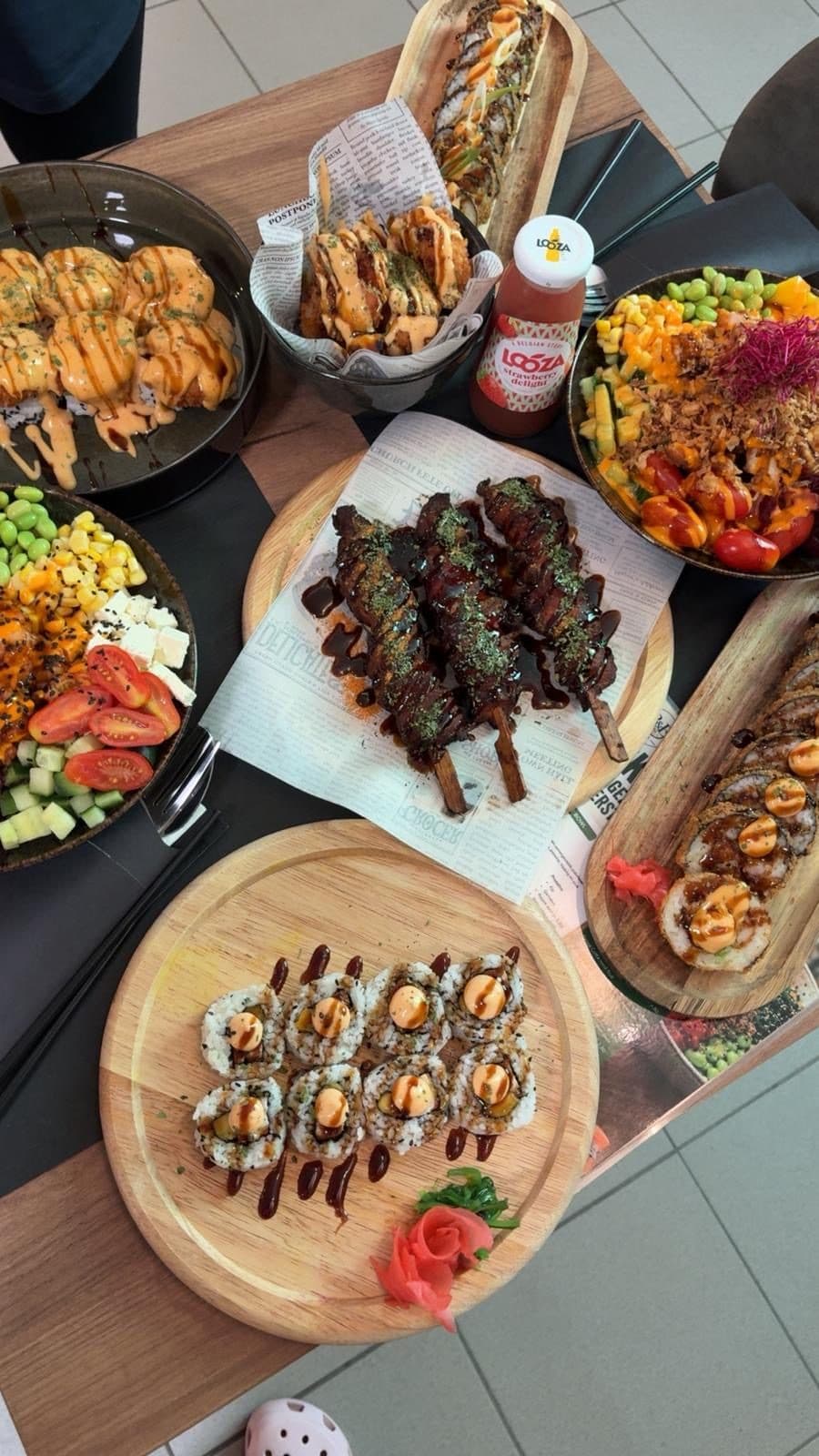 Sushi rolls, gefrituurde snacks en een pokébowl op tafel